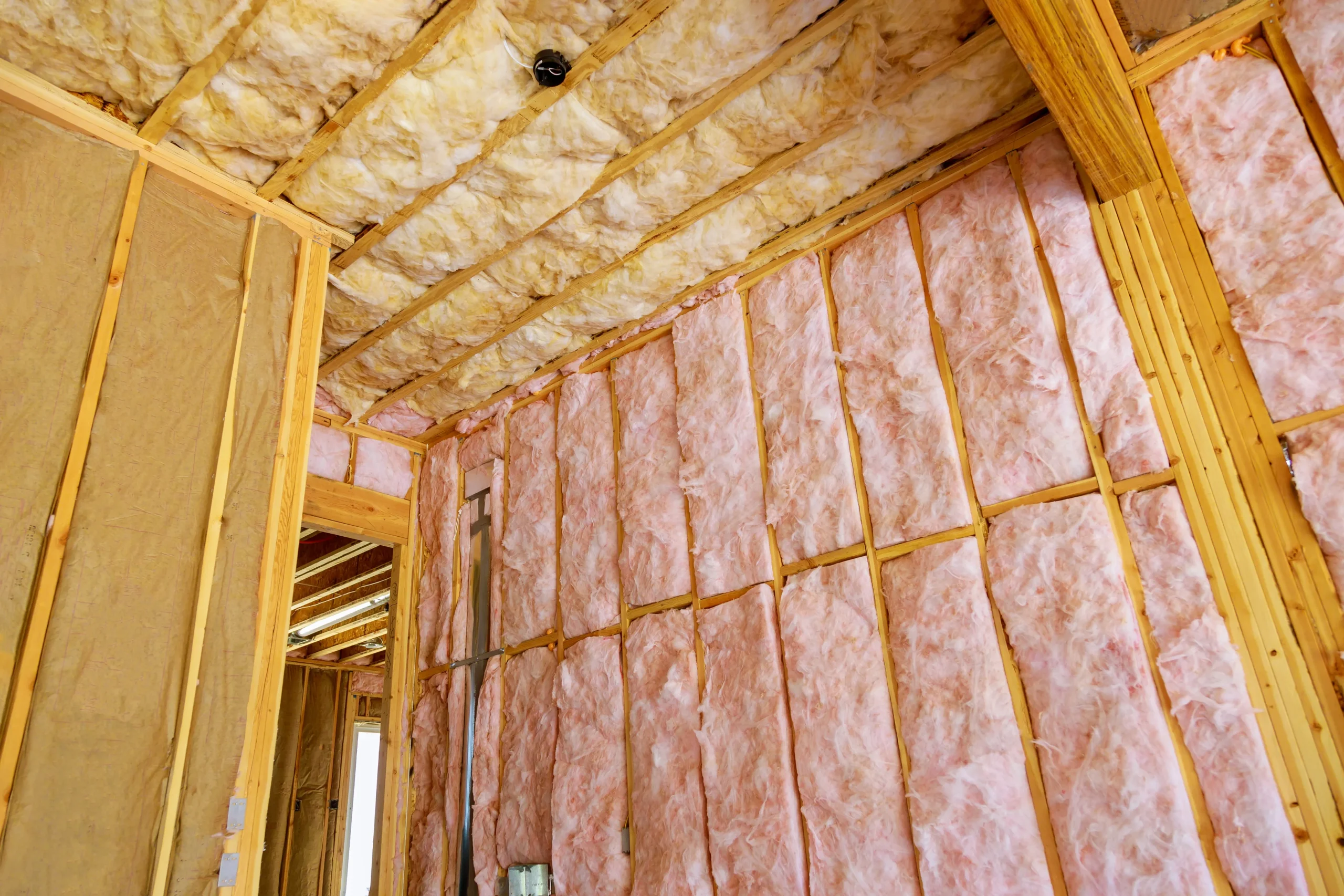 Fiberglass batt insulation installed between wall studs and roof rafters during residential home construction